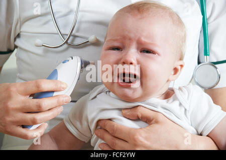 Krankenschwester, Einnahme von Weinen des Babys Temperatur mit Digitalthermometer Stockfoto