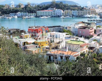 Mit Blick auf den Hafen von Ischia Porto auf tiefstehende Sonne. Die dunkle Farbe des Meeres macht einen schönen Kontrast mit dem helleren Blau des Himmels. Im Hintergrund die Insel Procida und den Vesuv. Stockfoto