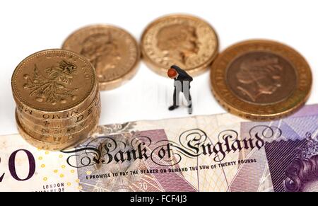 Eine Miniatur männliche Figur in einem Anzug steht neben Pfund-Münzen und einen 20-Pfund-Note zeigt die Worte Bank of England Stockfoto