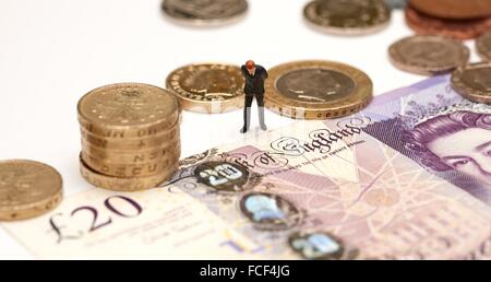 Eine Miniatur männliche Figur in einem Anzug steht neben Pfund-Münzen und einen 20-Pfund-Note zeigt die Worte Bank of England Stockfoto