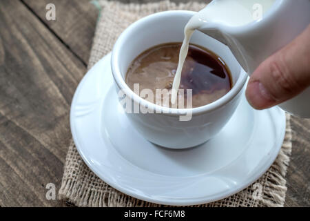 Gießt Milch in eine Tasse Kaffee, Nahaufnahme Stockfoto