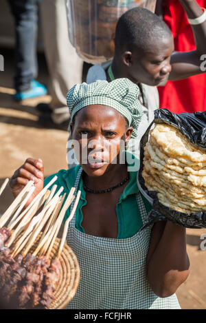 Straßenverkäufer verkaufen waren Menschen in den lokalen Bussen vorbei durch die Dörfer auf dem Weg heraus aus Kampala, Uganda, Afrika Stockfoto