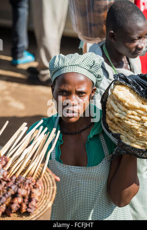 Straßenverkäufer verkaufen waren Menschen in den lokalen Bussen vorbei durch die Dörfer auf dem Weg heraus aus Kampala, Uganda, Afrika Stockfoto