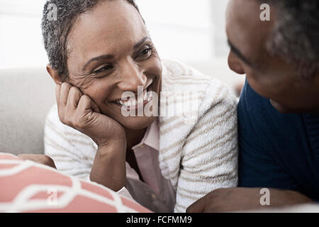 Ein paar, Mann und Frau liegend auf dem Bauch lachen einander an. Stockfoto