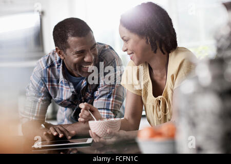 Ein Mann und eine Frau, ein paar in ihrer Küche sowohl Blick auf eine digital-Tablette. Stockfoto