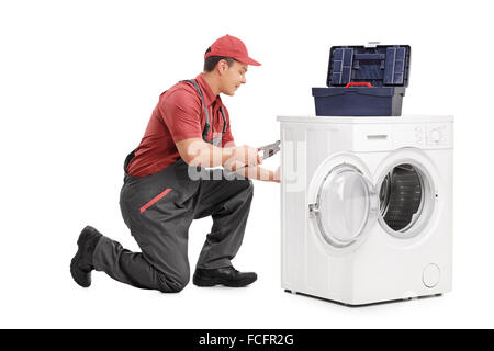 Studioaufnahme von einem jungen männlichen Arbeitnehmer Reparatur einer Waschmaschine isoliert auf weißem Hintergrund Stockfoto