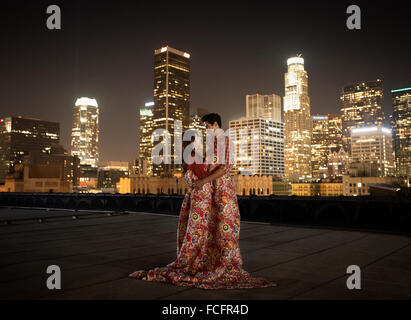 Ein paar auf einer Dachterrasse mit Blick auf Los Angeles in der Nacht, Warpped in decken. Stockfoto