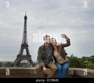 Ein paar sitzen nebeneinander nehmen eine selfy mit dem Eiffelturm im Hintergrund. Stockfoto