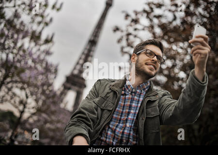 Ein Mann sitzt auf einer Parkbank in der Champs de Mars unter dem Eiffelturm. Stockfoto