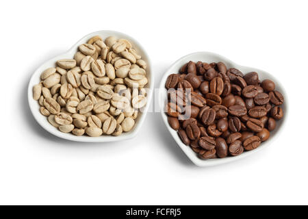 Herzförmige Schalen mit indischen Malabar grüne ungerösteten und braun gerösteten Kaffeebohnen auf weißem Hintergrund Stockfoto
