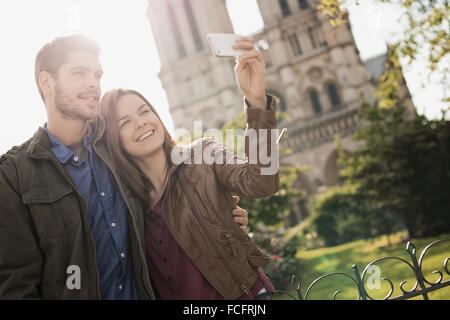 Zwei Menschen, ein paar stehen dicht beieinander unter einem selfy außerhalb der historischen Kathedrale Notre Dame in Paris. Stockfoto