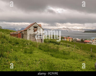 Altes Haus auf einem grünen Hügel mit Blick auf das Wasser in Isafjördur Island aufgeschlüsselt. Stockfoto