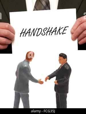 Handshake-Konzept 2 Miniatur Figuren in Anzügen, die Hände schütteln Stockfoto