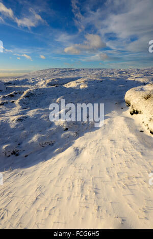 Verschneite Moorlandschaft neben der Pennine Way über Glossop in Derbyshire auf eine atemberaubende Winterlandschaft am Abend bei Sonnenuntergang. Stockfoto