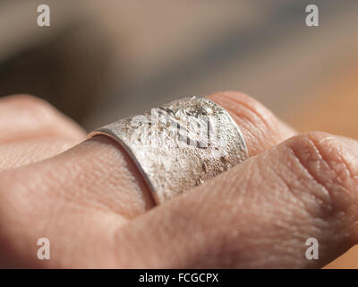 Handwerklichen Silberring hautnah am Mittelfinger von Frauenhand. Ring von Aaron Maya gemacht. Stockfoto