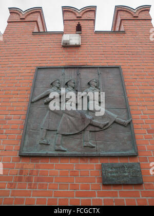 Gedenktafel von drei marschierenden Soldaten mit Gewehren auf roten Backsteinmauer außerhalb dem Roten Platz in Moskau, Russland. Stockfoto