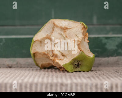 Faulenden grünen angebissene Apfel auf Zement-Tafel. Stockfoto