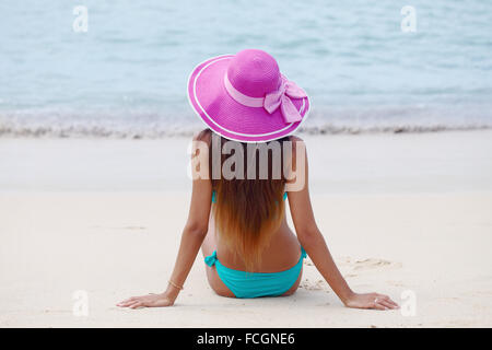 Frau in großen Hut sitzt am Strand am Meer Stockfoto