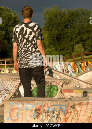 Junge männliche stehend mit Rücken zur Kamera im Skateboard-Park bedeckt Graffiti in Bronte, Oakville, Ontario, Kanada. Stockfoto