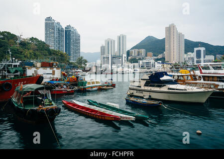 Boote am Ap Lei Chau und Blick auf die Wolkenkratzer und Berge in Hong Kong, Hong Kong verankert. Stockfoto