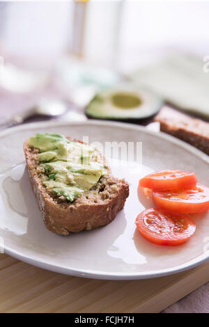 Frische Avocado auf dicken Scheiben Vollkornbrot mit Tomaten. Stockfoto