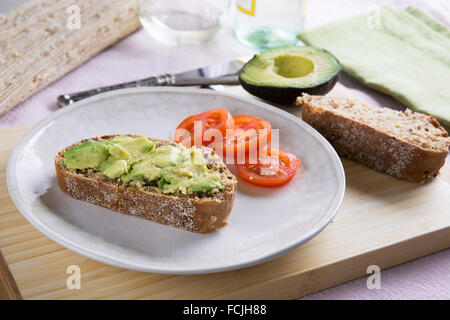 Frische Avocado auf dicken Scheiben Vollkornbrot mit Tomaten. Stockfoto