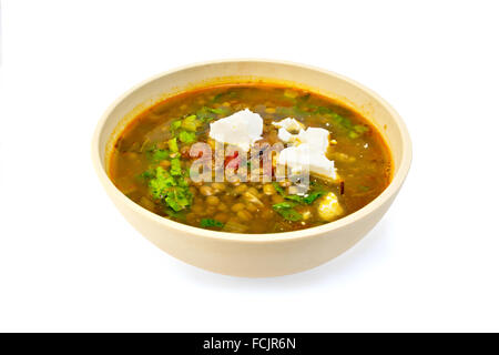 Linsensuppe mit Spinat, Tomaten und Feta-Käse in einer gelben Schale isoliert auf weißem Hintergrund Stockfoto