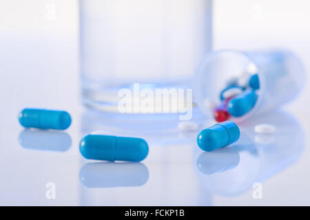 Pillen und ein Glas Wasser auf der Oberfläche. Stockfoto