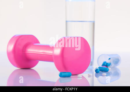 Hantel, Pillen und Glas Wasser auf der Oberfläche. Stockfoto