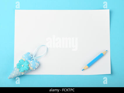 Weiße Papier-Schuldbrief mit winzigen Textil Spielzeug Herz und kleinen Bleistift auf zarten blauen Hintergrund Stockfoto