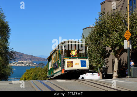 Cable Car an der Hyde Street an der Kreuzung mit der Lombard Street, mit Fernsicht auf der Insel Alcatraz, San Francisco, Kalifornien, USA Stockfoto