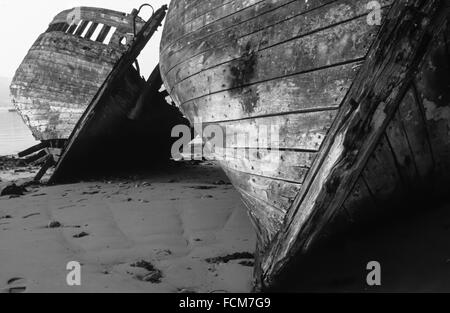 Zwei hölzerne Schiffswracks liegen auf der Seite und verschlechtern sich im Hafen von Camaret in der Bretagne Stockfoto