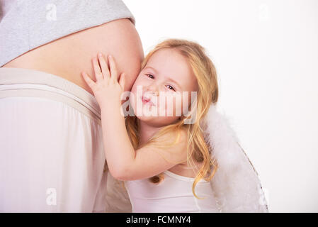 Schöne blonde Modell Haar Engel umarmt schwangeren Bauch. Stockfoto