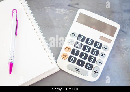 Taschenrechner, Notizblock und Stift auf grauem Hintergrund, Fotoarchiv Stockfoto