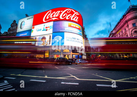 Busse und Taxis fahren vorbei an der berühmten Welt die Werbeschilder am Piccadilly Circus in London. Stockfoto