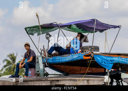 Zwei Männer entspannend auf Boot wie es segelt hinunter die Mekong-Delta Vietnam Stockfoto