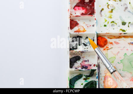 Fokus auf Wasser malen Pinsel Farbe auf Farbe Tablett mit leerem Papier auf linken Seite setzen Stockfoto