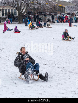 Vater und Kind Rodeln auf einen verschneiten Hang in einem öffentlichen Park im Winter, Berlin, Mitte, Volkspark am Weinbergsweg, Stockfoto