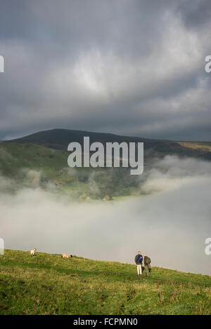 Zwei Wanderer stehen und bewundern Sie die Aussicht auf Nebel unten Mam Tor in Castleton, Derbyshire. Stockfoto