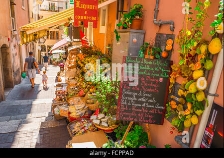 Taormina Siziliens Lebensmittelgeschäft, Blick auf Eltern und Kinder, die an einem bunten Lebensmittelgeschäft in einer engen Straße in der Nähe des Corso Umberto I in Taormina, Sizilien vorbeikommen. Stockfoto