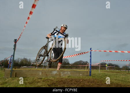 Abingdon, Oxfordshire, Vereinigtes Königreich. 24. Januar 2016. Das Wetter war trocken und sonnig, ideal für die Wessex Cyclo-Cross-Rennen in Abingdon Flugplatz. Cyclo-Cross ist Cross-Country Rennen auf Fahrrädern. Manchmal haben Menschen ihr Fahrrad durch schlammigen Bedingungen durchzuführen. Stephen Charter of Oxford trägt sein Fahrrad über die Bretter auf seine vierte Runde des Rennens. Sidney Bruere/Alamy Live-Nachrichten. Stockfoto