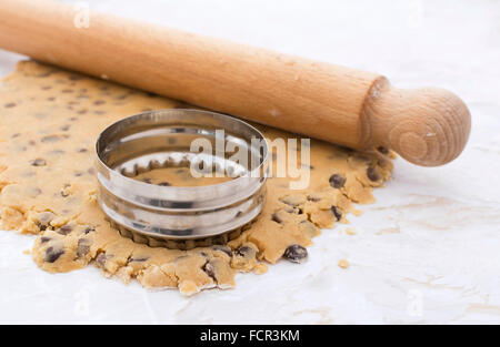 Ausstecher und hölzernen Nudelholz auf Erdnussbutter und Schokolade-Chip-Cookie-Teig ausgerollt Stockfoto