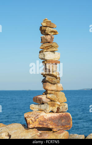 Stapel von Steinen Gleichgewicht über blauem Meer und blauem Himmel am Abend Stockfoto