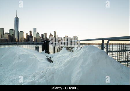 Jersey City, USA. 24. Januar 2016. Eine Bank am Wasser bedeckt fast vollständig im Schnee mit der NYC Skyline im Hintergrund. Die Sonne geht über Jersey City, wo die Jonas Blizzard die Straßen, im Schnee Credit verlassen hat: Elizabeth Wake/Alamy Live News Stockfoto