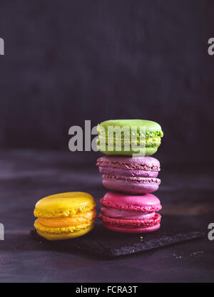 Bunte französische Macarons auf dunklen rustikaler Hintergrund, Tiefenschärfe, getönt Stockfoto