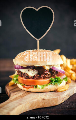 Saftiges Rindfleischburger und Pommes Frites auf Holzbrett Stockfoto