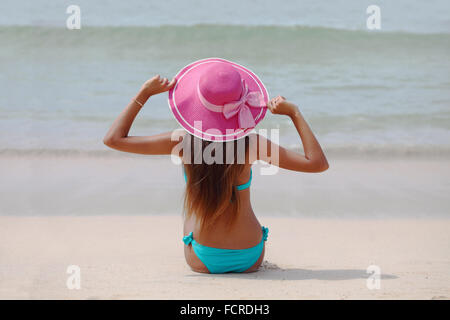 Frau in großen Hut sitzt am Strand am Meer Stockfoto