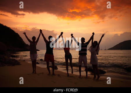 Gruppe von Menschen feiern am Strand bei Sonnenuntergang Stockfoto