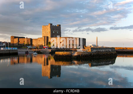 Norman Mittelalterburg in Carrickfergus, Nordirland und seine Spiegelung im Wasser bei Sonnenuntergang. Stockfoto