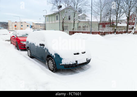 Autos, die schneebedeckten geparkt entlang der verschneiten Straße in Finnland Stockfoto